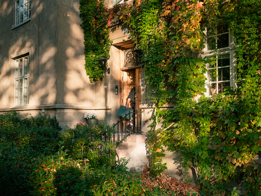 Electrician entering a doorway in a wall overgrown with foliage at St Hanshaugen Oslo.